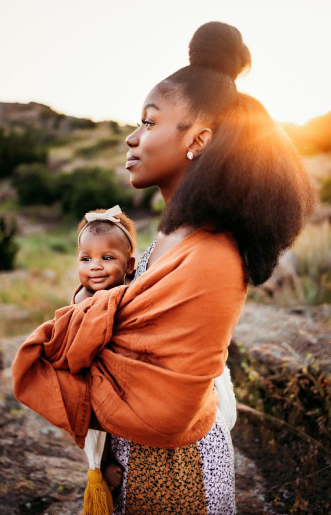 Family & Maternity Photographer, a mother gazes confidently as she holds her newborn baby outdoors at golden hour