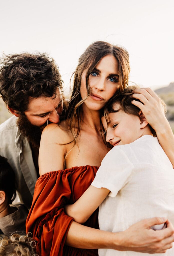 Family Photographer, a mother holds her son close as dad leans in from behind outside